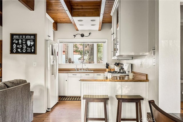 kitchen with gas range, sink, wooden ceiling, white cabinetry, and white fridge with ice dispenser