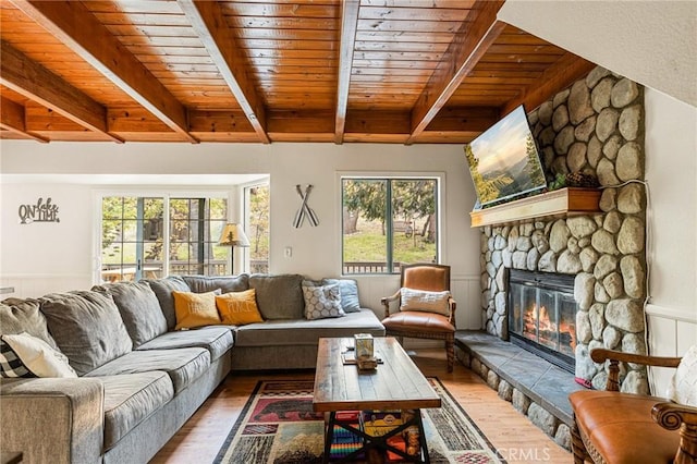 living room featuring wood-type flooring, a stone fireplace, and wooden ceiling