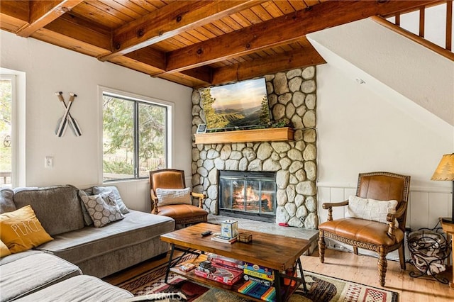 living room with wood ceiling, beam ceiling, wood finished floors, and a stone fireplace