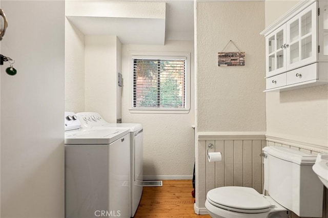 bathroom featuring washer and clothes dryer, toilet, and hardwood / wood-style flooring