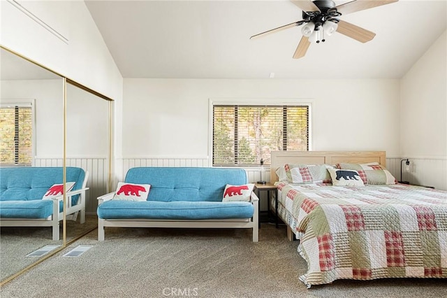 carpeted bedroom with a closet, ceiling fan, lofted ceiling, and wood walls