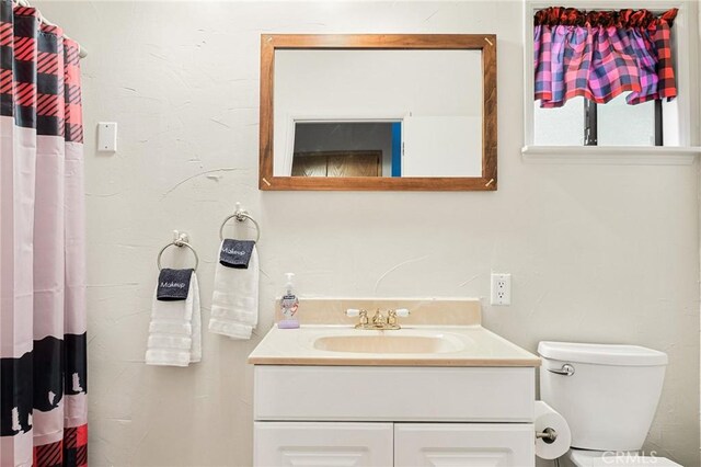 bathroom featuring a shower with curtain, vanity, and toilet