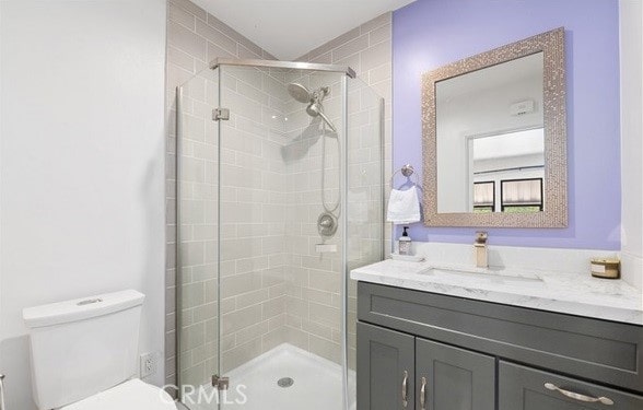 bathroom with vanity, toilet, and a shower with door