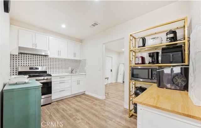 kitchen with appliances with stainless steel finishes, light wood-type flooring, backsplash, and white cabinetry