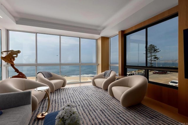 sunroom featuring a water view and a tray ceiling