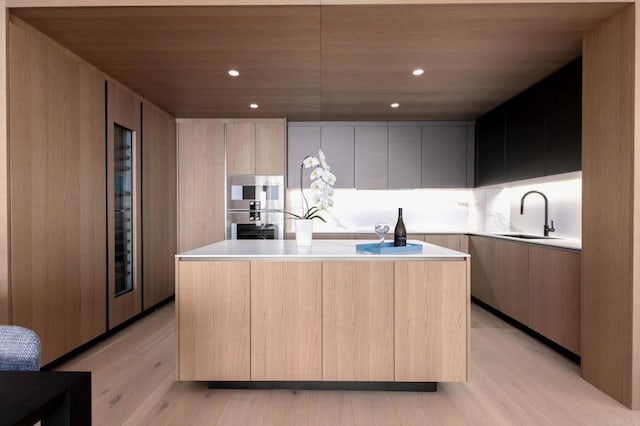 kitchen featuring light brown cabinetry, light wood-type flooring, sink, and a kitchen island