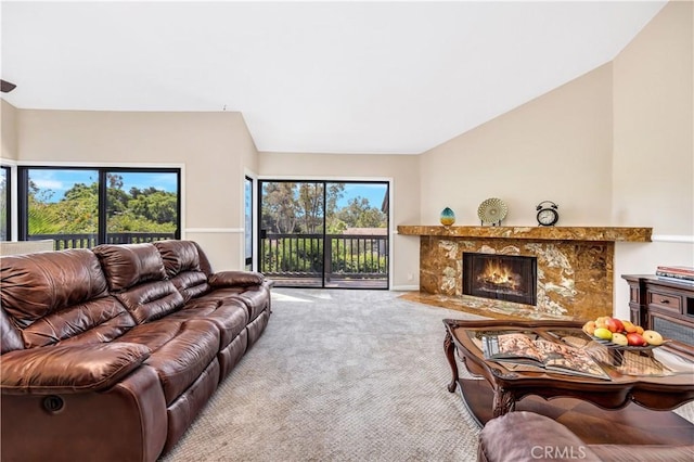 carpeted living room with plenty of natural light, a high end fireplace, and vaulted ceiling