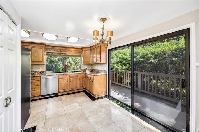 kitchen with light stone countertops, appliances with stainless steel finishes, an inviting chandelier, and a healthy amount of sunlight