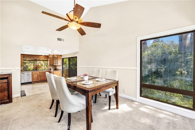 carpeted dining room with ceiling fan and high vaulted ceiling