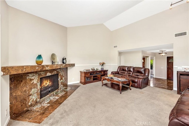 carpeted living room featuring a high end fireplace and lofted ceiling