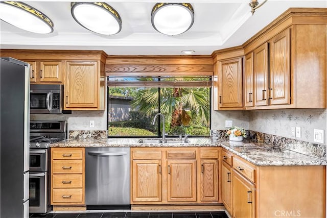 kitchen with appliances with stainless steel finishes, stone countertops, dark tile patterned floors, and sink