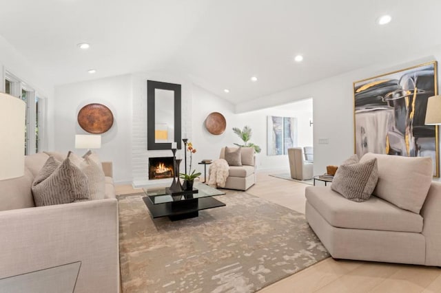 living room with vaulted ceiling and a large fireplace