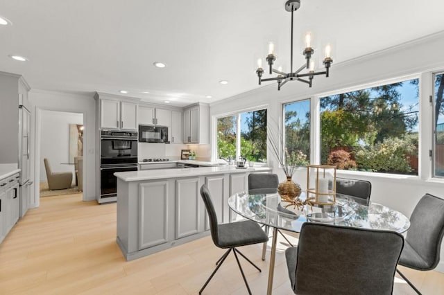 dining room featuring an inviting chandelier, crown molding, light hardwood / wood-style flooring, and a healthy amount of sunlight