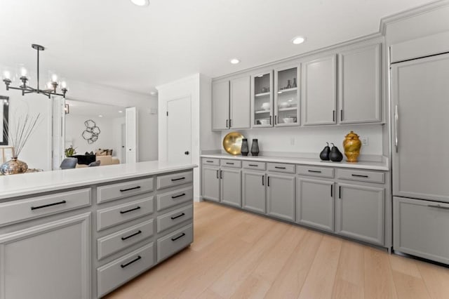 kitchen with gray cabinetry, decorative light fixtures, and light hardwood / wood-style flooring