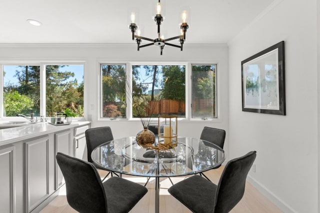 dining area featuring ornamental molding, sink, an inviting chandelier, and light hardwood / wood-style flooring