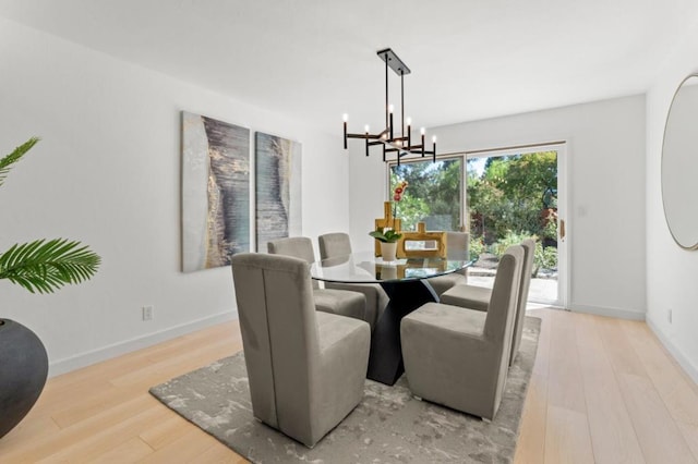 dining space with light hardwood / wood-style floors and a chandelier