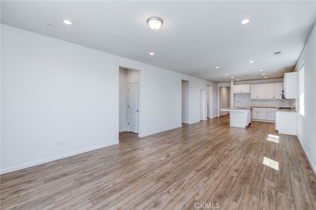 unfurnished living room featuring light hardwood / wood-style floors and sink