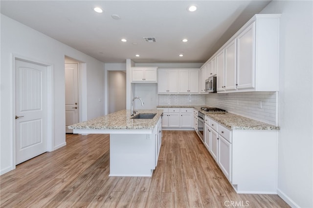 kitchen featuring white cabinets, sink, a center island with sink, light hardwood / wood-style flooring, and stainless steel appliances