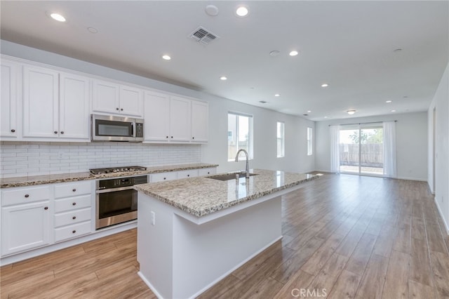 kitchen featuring sink, a kitchen island with sink, white cabinetry, stainless steel appliances, and light wood-type flooring