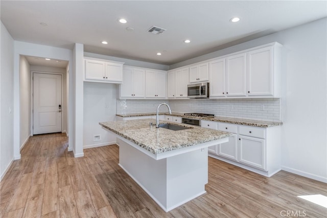 kitchen featuring stainless steel appliances, white cabinets, light hardwood / wood-style floors, and sink