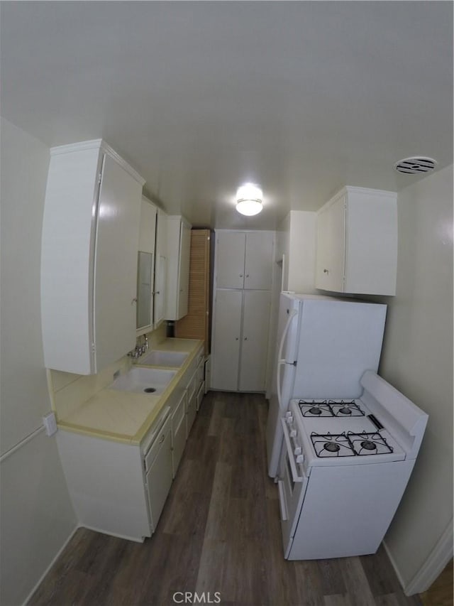 kitchen featuring white appliances, visible vents, dark wood-style floors, light countertops, and a sink