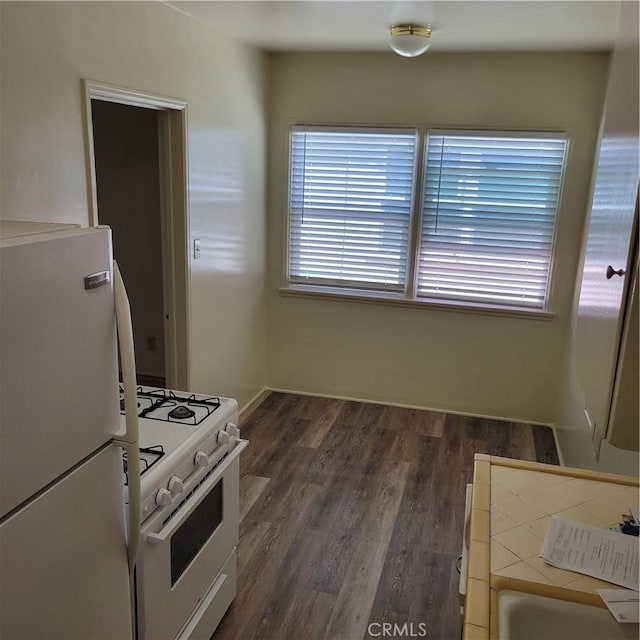 kitchen with a healthy amount of sunlight, white appliances, baseboards, and dark wood finished floors