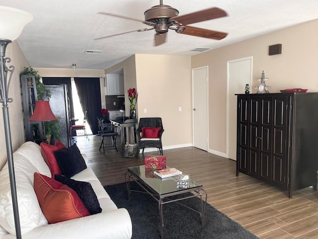 living room with a textured ceiling, wood-type flooring, and ceiling fan