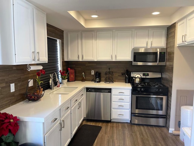 kitchen featuring decorative backsplash, white cabinets, appliances with stainless steel finishes, dark wood-type flooring, and sink