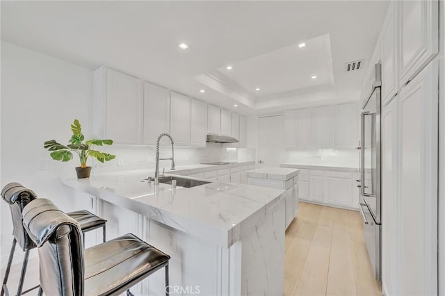 kitchen with a breakfast bar, white cabinets, kitchen peninsula, and sink