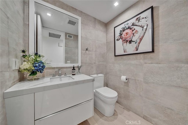 bathroom featuring vanity, toilet, and tile walls