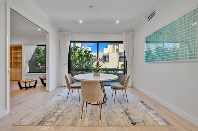 dining room with plenty of natural light, light wood-type flooring, and ornamental molding