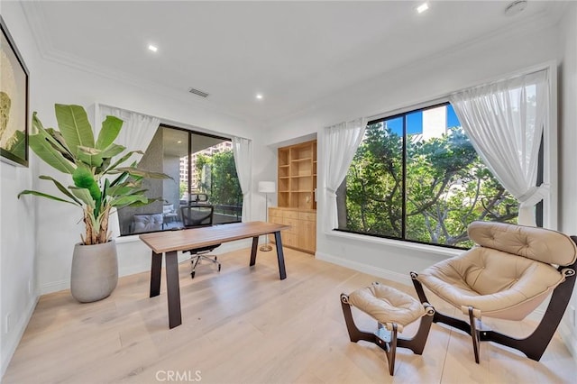 home office with built in shelves, light wood-type flooring, and ornamental molding