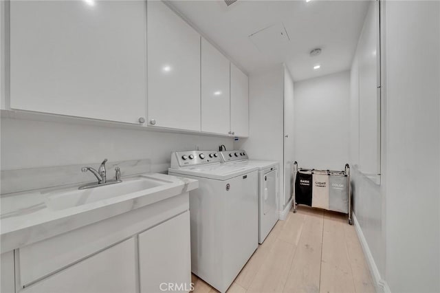 washroom featuring sink, washer and clothes dryer, cabinets, and light wood-type flooring