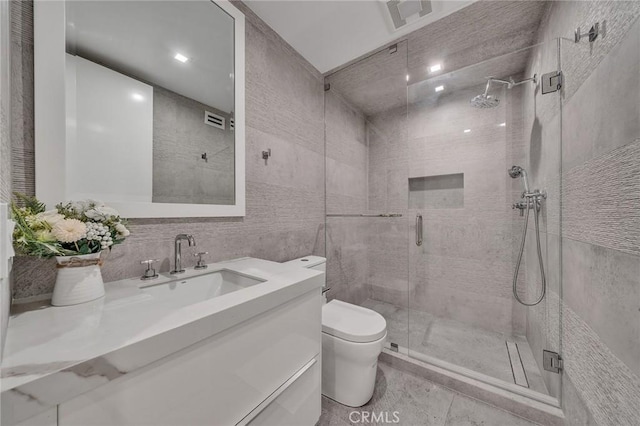 bathroom with tile walls, vanity, an enclosed shower, and toilet