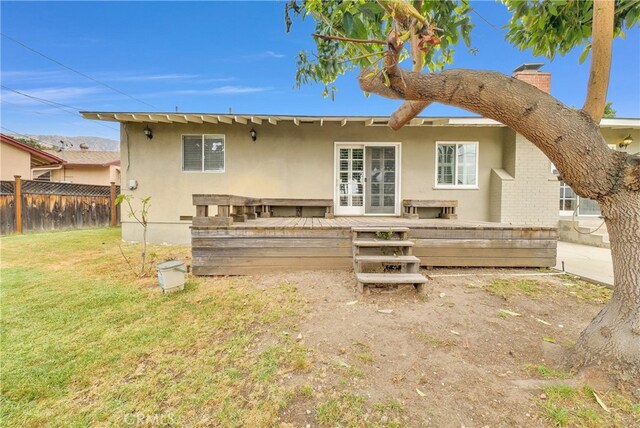 rear view of property with a lawn and a wooden deck