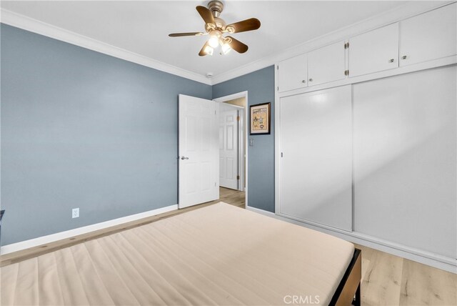 unfurnished bedroom with ceiling fan, light wood-type flooring, ornamental molding, and a closet