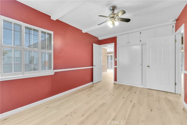 unfurnished bedroom with ceiling fan, a closet, beamed ceiling, and light hardwood / wood-style floors