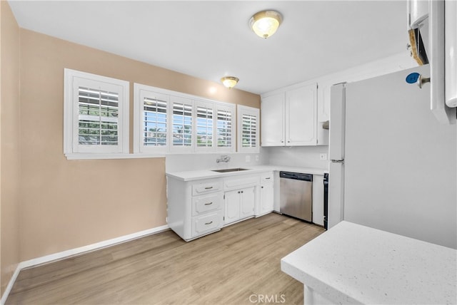 kitchen with stainless steel dishwasher, plenty of natural light, white refrigerator, and white cabinets