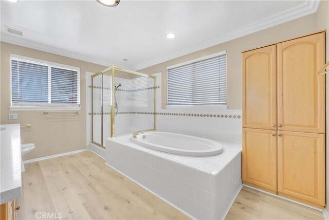 bathroom with plus walk in shower, hardwood / wood-style flooring, toilet, and ornamental molding