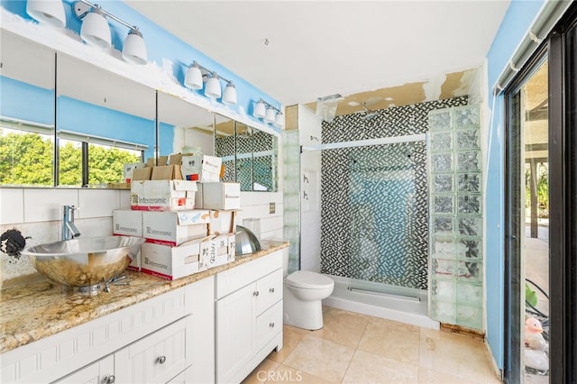 bathroom featuring vanity, tile patterned floors, toilet, and tiled shower