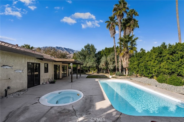 view of swimming pool with an in ground hot tub, a mountain view, and a patio area