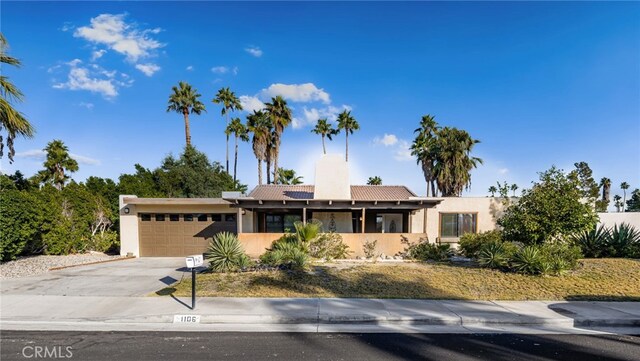 single story home featuring solar panels and a garage