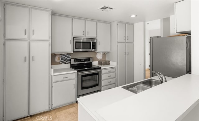 kitchen with sink, tasteful backsplash, light tile patterned floors, stainless steel appliances, and white cabinets