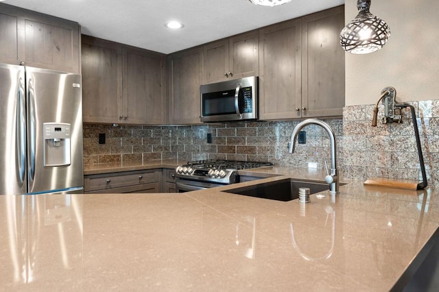 kitchen with tasteful backsplash, sink, hanging light fixtures, and appliances with stainless steel finishes