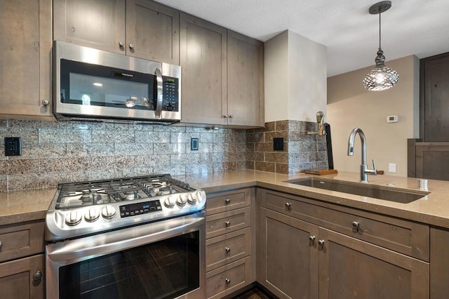 kitchen featuring sink, decorative backsplash, decorative light fixtures, and appliances with stainless steel finishes