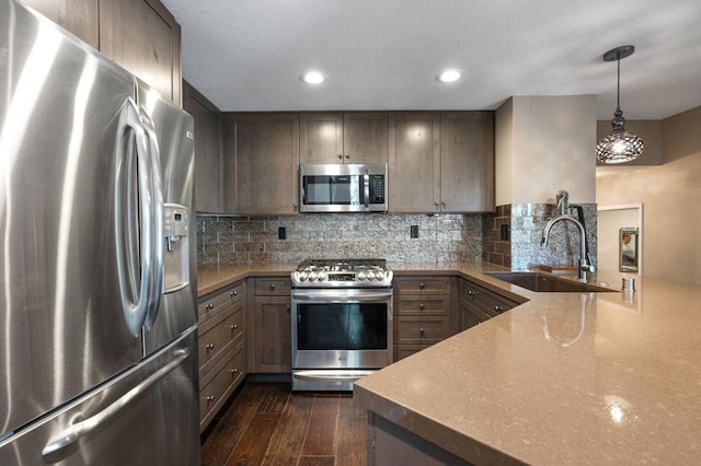 kitchen featuring pendant lighting, sink, appliances with stainless steel finishes, backsplash, and dark hardwood / wood-style flooring