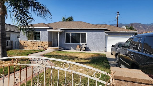 single story home with a front yard, a mountain view, and a garage