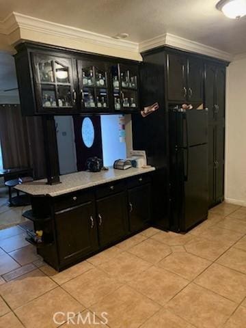 bar with light tile patterned flooring, black fridge, and ornamental molding