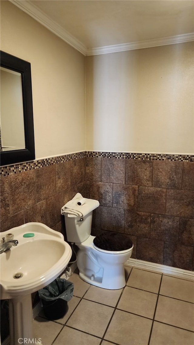 bathroom with tile patterned floors, crown molding, tile walls, and toilet