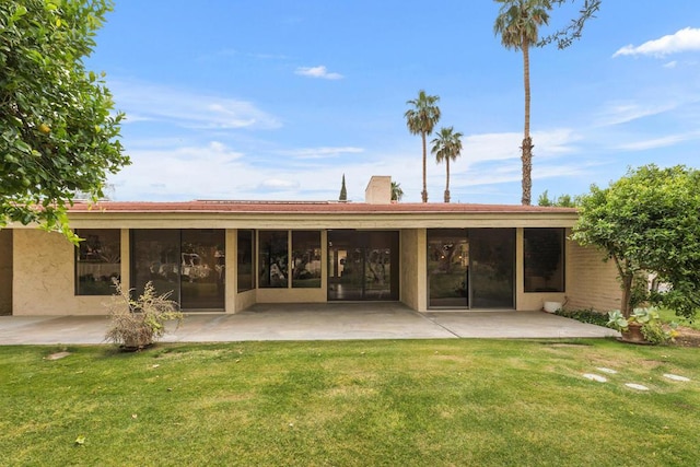 back of property with a lawn and a patio